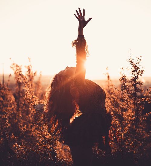 Woman in a graceful stretching pose, cyan glow illuminating her silhouette